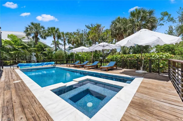 View of swimming pool with a wooden deck and a pool with connected hot tub