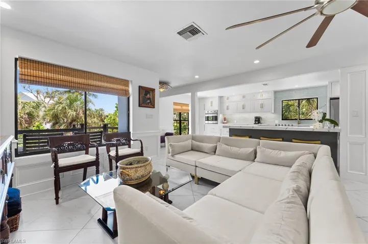 Living area with recessed lighting, light marble finish flooring, ceiling fan, a decorative wall, and wainscoting