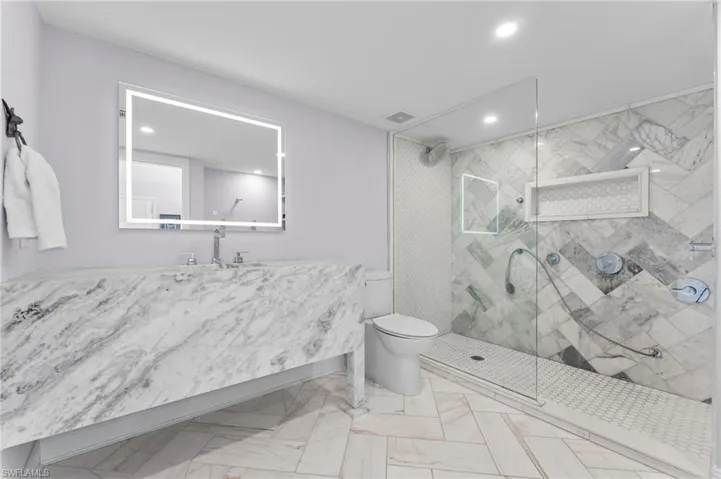 Bathroom with a marble finish shower, vanity, and recessed lighting