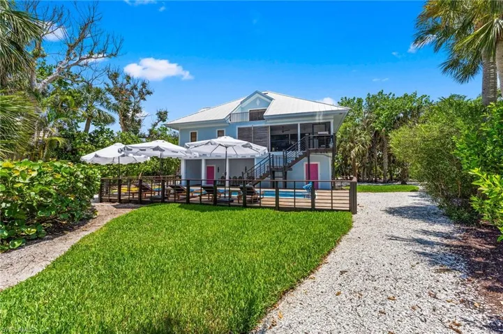 Back of property featuring stairway, an outdoor pool, a metal roof, and a sunroom