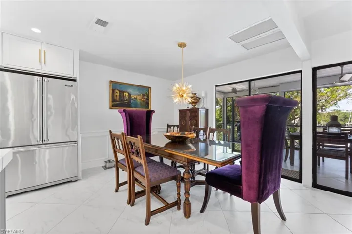 Dining area with light marble finish flooring, a wainscoted wall, a chandelier, and a decorative wall