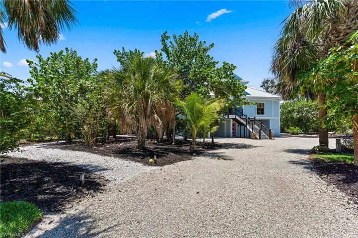 View of front of house with stairway, driveway, and a metal roof