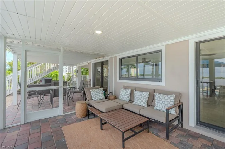 Sunroom featuring outdoor dining space, a patio, and an outdoor hangout area - Virtually Edited Image