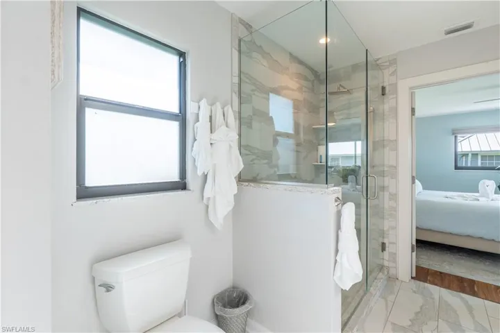 Bathroom featuring connected bathroom, a shower stall, and marble finish floors - Virtually Edited Image