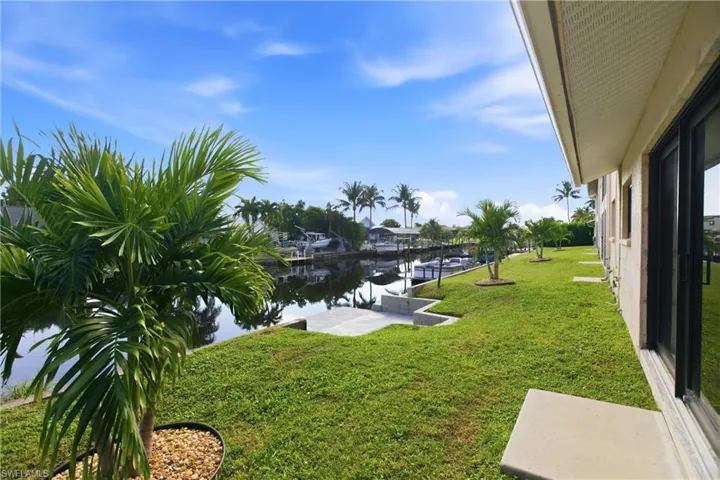 View of green lawn featuring a water view, a boat dock, and boat lift