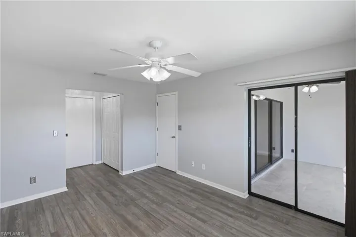 Unfurnished bedroom featuring wood finished floors, ceiling fan, and two closets