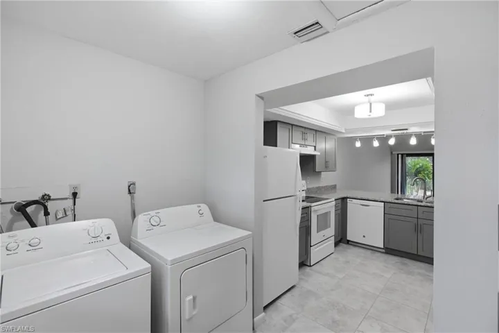 Laundry room with washing machine and dryer and light tile patterned flooring