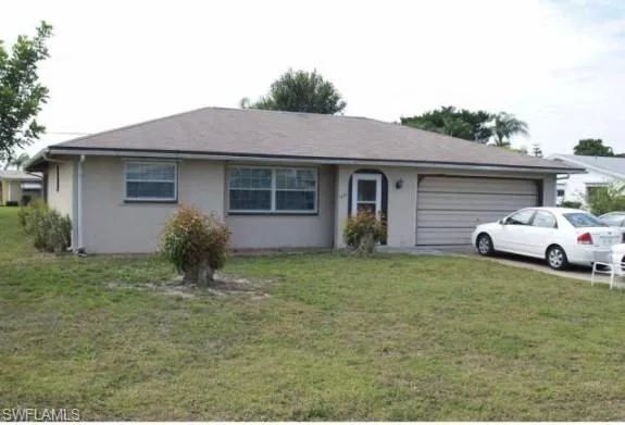 Single story home featuring a front yard and a garage