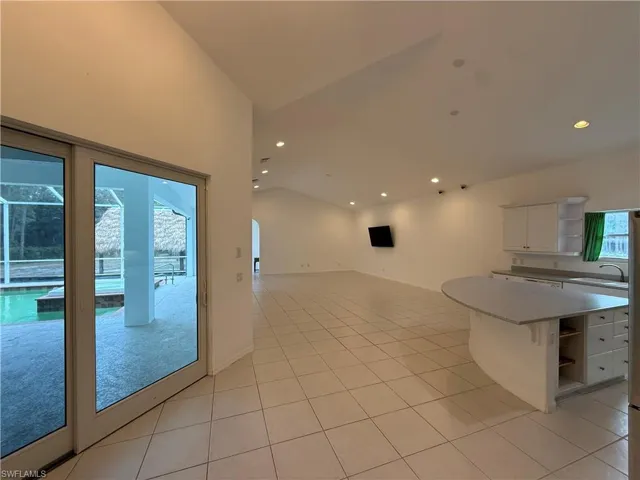 Kitchen featuring open shelves, lofted ceiling, white cabinetry, arched walkways, and open floor plan