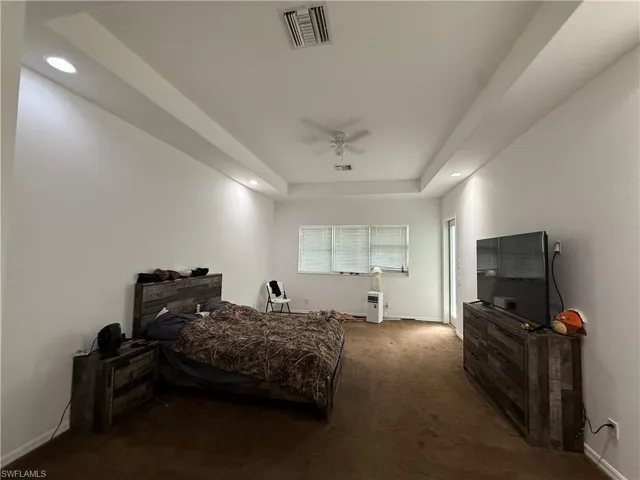 Bedroom featuring dark carpet, a tray ceiling, recessed lighting, and a ceiling fan