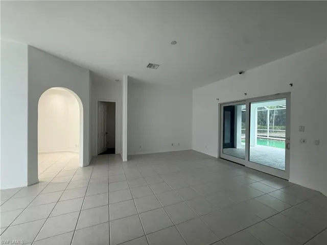 Unfurnished room featuring arched walkways and light tile patterned floors