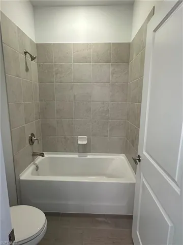 Bathroom with hardwood / wood-style flooring, toilet, and tiled shower / bath