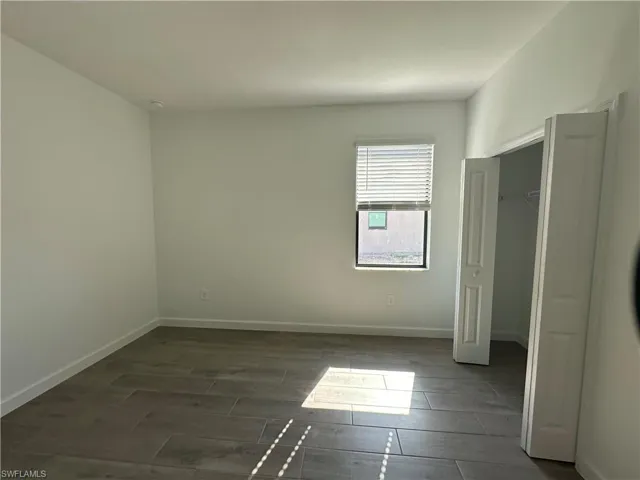 Unfurnished bedroom with dark hardwood / wood-style floors and a closet