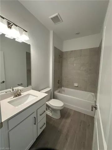 Full bathroom featuring oversized vanity, hardwood / wood-style flooring, toilet, and tiled shower / bath combo