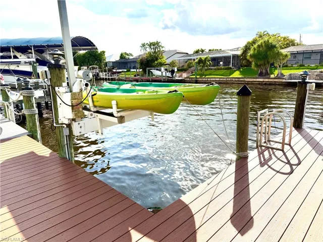 Dock area featuring a water view, boat lift, and a residential view