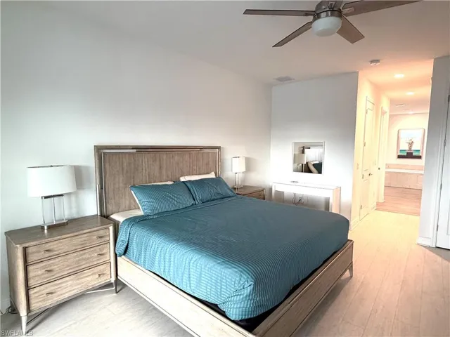 Bedroom featuring a ceiling fan, light wood finished floors, connected bathroom, and a closet
