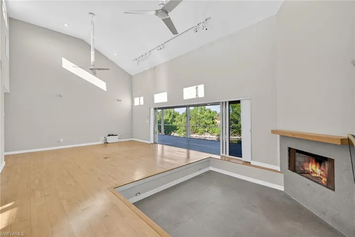 Unfurnished living room with a high ceiling, wood finished floors, a lit fireplace, and a water view