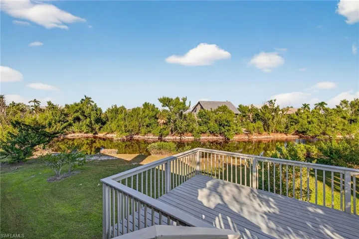 Wooden terrace with a yard, a water view, and view of scattered trees