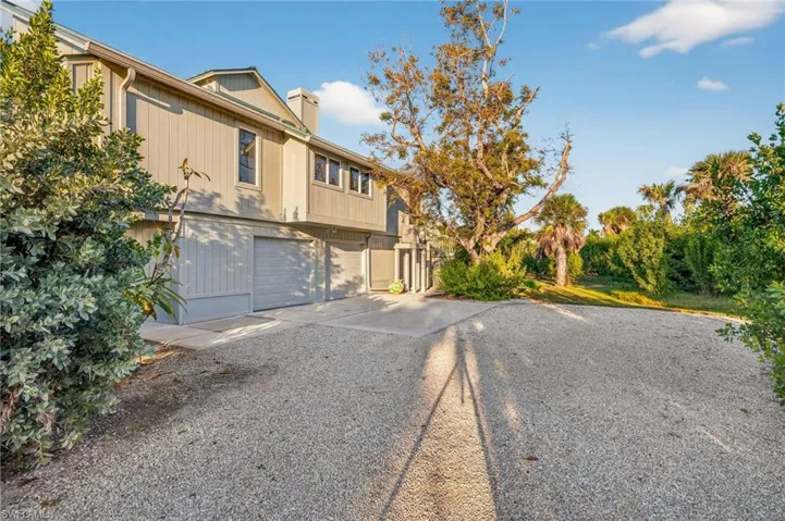 View of front of house with driveway, a chimney, and a garage