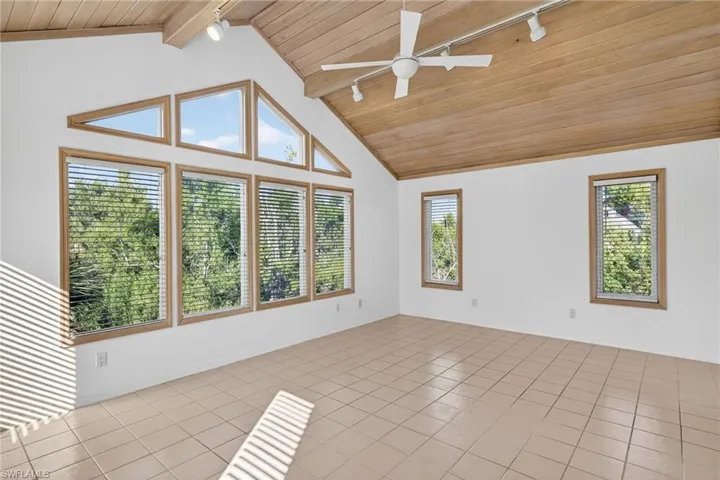 Unfurnished room with track lighting, a wood ceiling with exposed beams, tile patterned floors, ceiling fan, and high vaulted ceiling