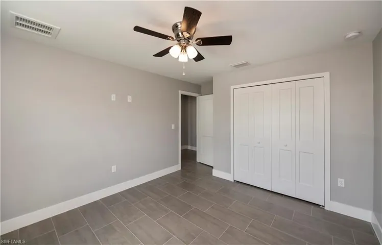 Unfurnished bedroom with a ceiling fan, a closet, visible vents, and baseboards