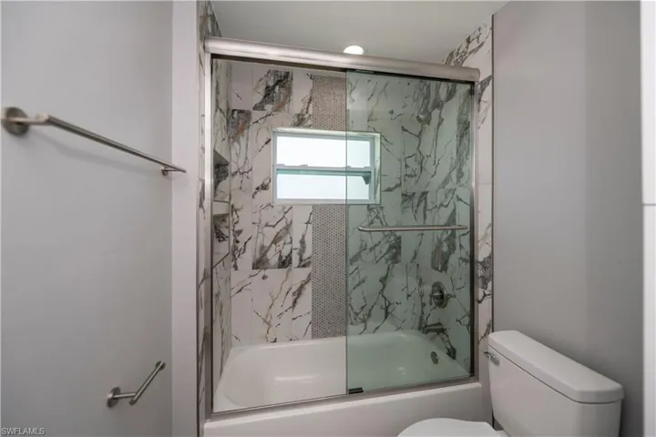 Full bathroom featuring toilet and combined bath / shower with glass door