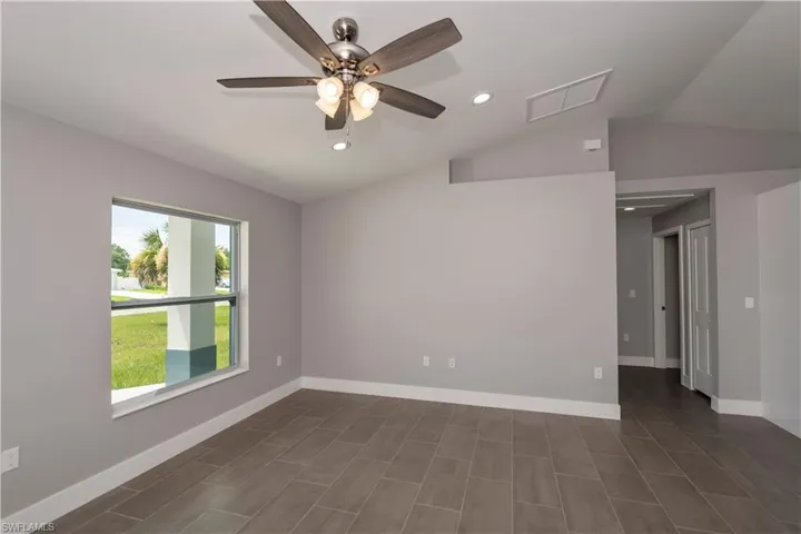 Empty room with recessed lighting, visible vents, vaulted ceiling, and baseboards