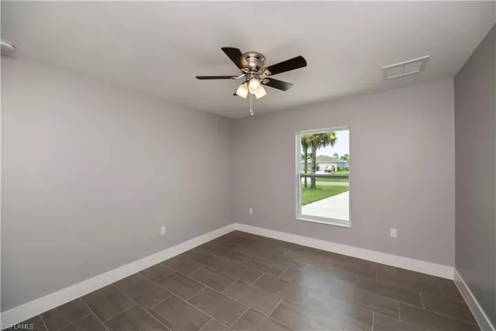 Spare room with baseboards, visible vents, and a ceiling fan