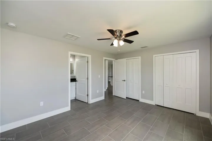 Unfurnished bedroom with visible vents, baseboards, and two closets