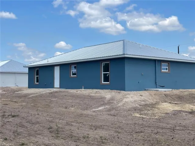 Rear view of house featuring metal roof and stucco siding
