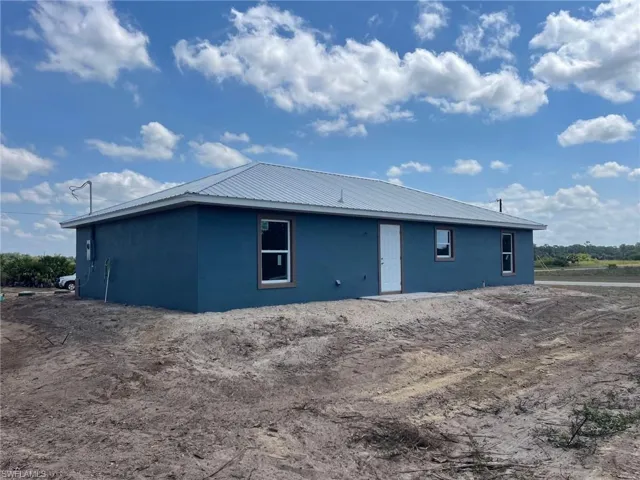 View of property exterior featuring stucco siding and metal roof