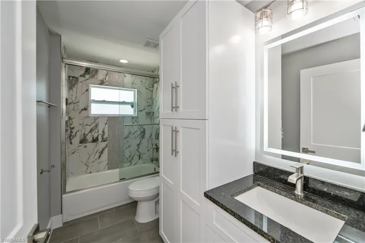 Bathroom featuring visible vents, vanity, toilet, and bath / shower combo with glass door