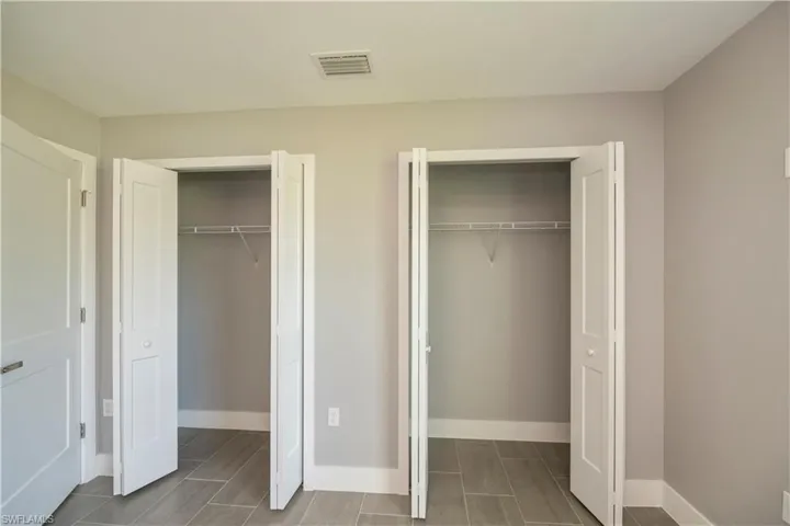 Unfurnished bedroom with baseboards, visible vents, and multiple closets