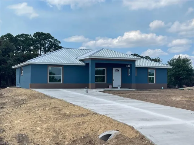 Single story home featuring metal roof, stucco siding, and a porch