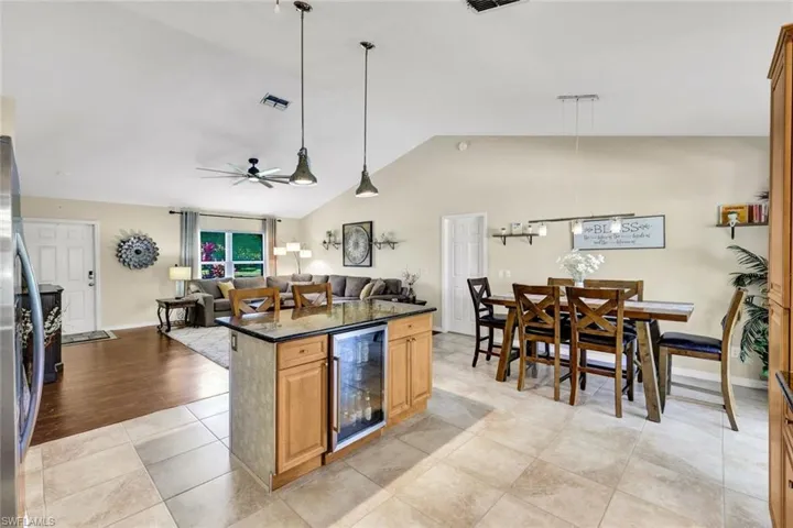 Kitchen with pendant lighting, dark stone counters, open floor plan, wine cooler, and light tile patterned flooring