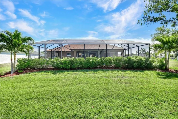 View of grassy yard with a sunroom and glass enclosure