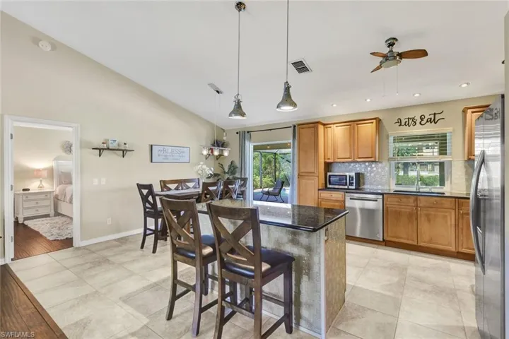 Kitchen with a breakfast bar area, ceiling fan, wood finish cabinetry, stainless steel appliances, and vaulted ceiling