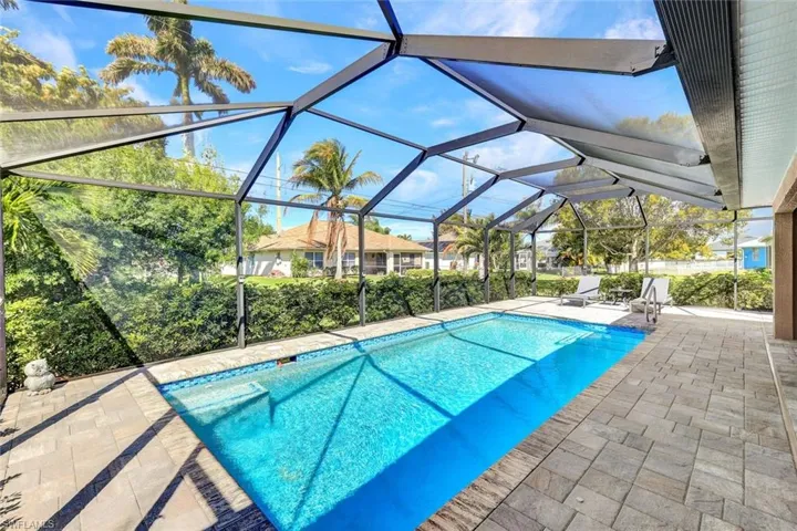 Outdoor pool with a sunroom, a patio, and glass enclosure