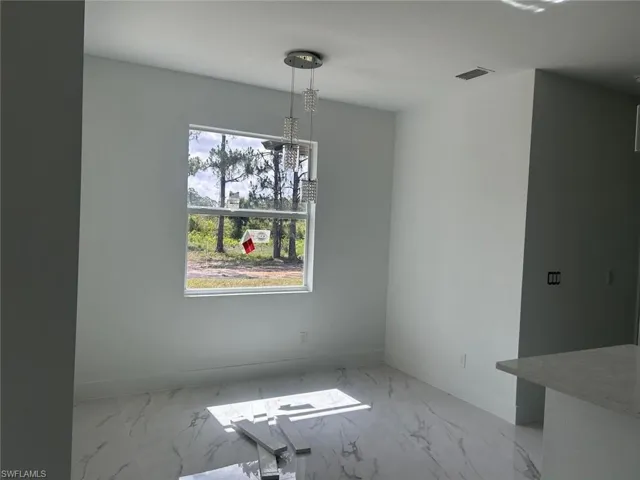 Unfurnished dining area featuring baseboards and marble look tile flooring