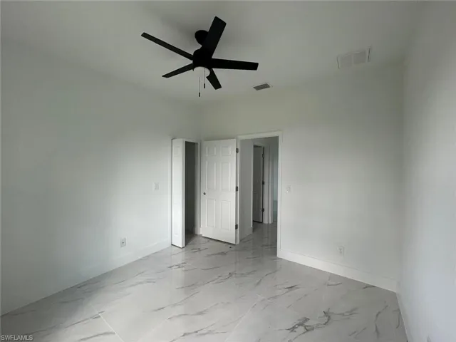 Unfurnished room featuring a ceiling fan and light marble finish floors