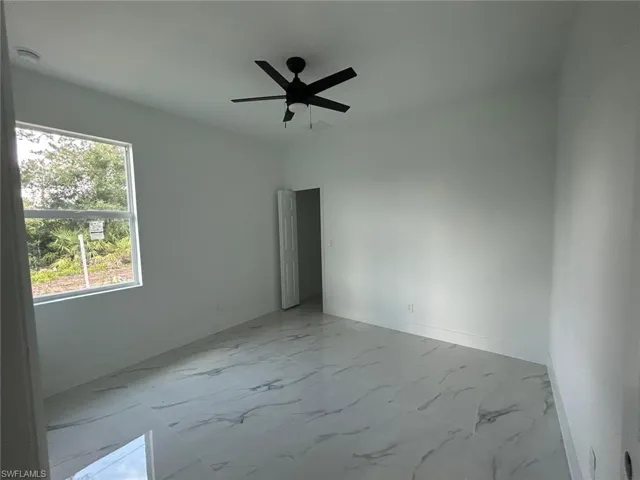 Unfurnished room featuring light marble finish floors and ceiling fan