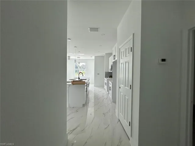 Hall with light marble finish floors and a sink