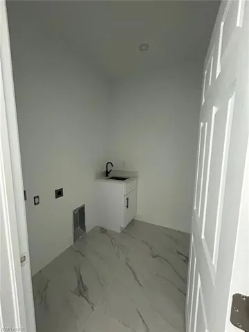 Washroom featuring hookup for an electric dryer and light marble finish flooring