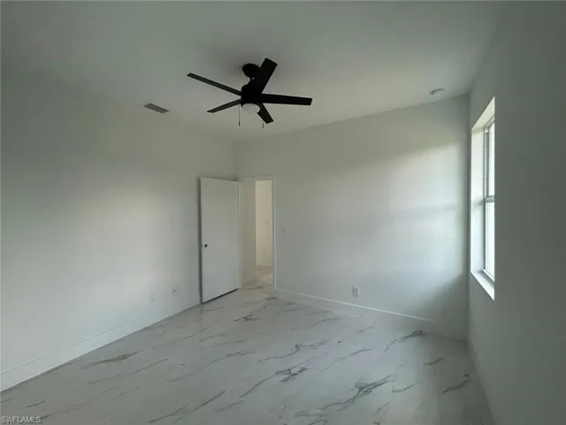 Empty room featuring light marble finish flooring and ceiling fan