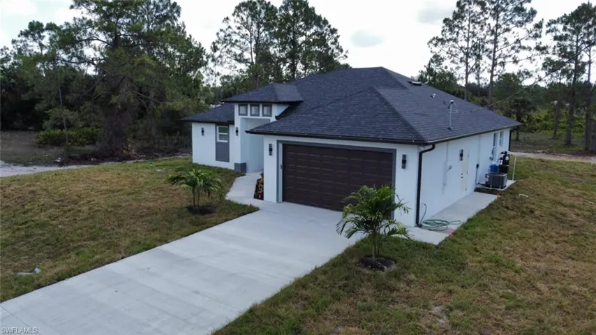 View of front of house with stucco siding, an attached garage, roof with shingles, concrete driveway, and a front yard