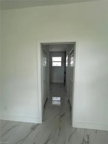 Hallway featuring light marble finish floors and baseboards