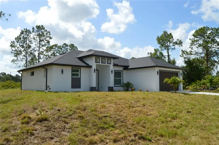 Prairie-style house with an attached garage, a front yard, and stucco siding