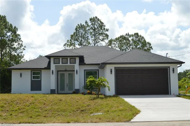View of front facade featuring french doors, an attached garage, stucco siding, concrete driveway, and a front yard