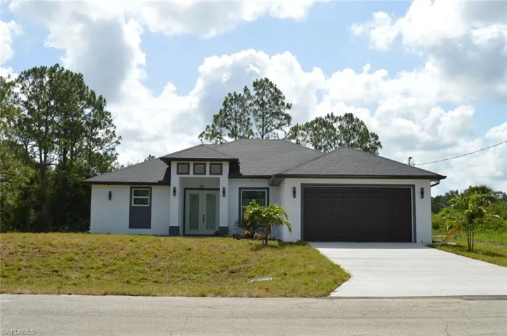 Prairie-style house featuring french doors, driveway, a garage, stucco siding, and a front yard
