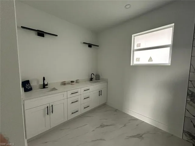 Bathroom featuring marble finish flooring and double vanity